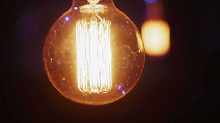A light bulb glows in a dark room