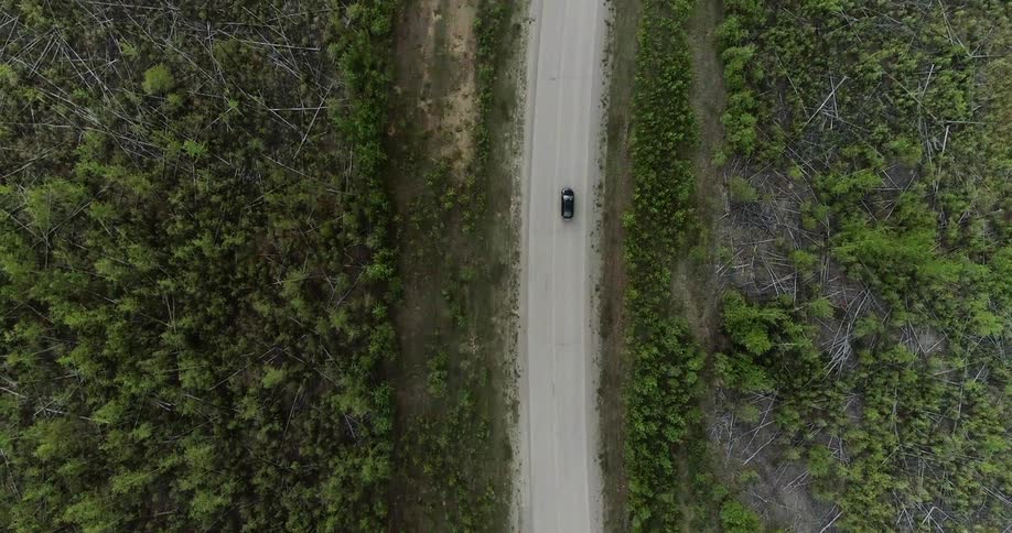 A vehicle is driving on a remote road in daylight