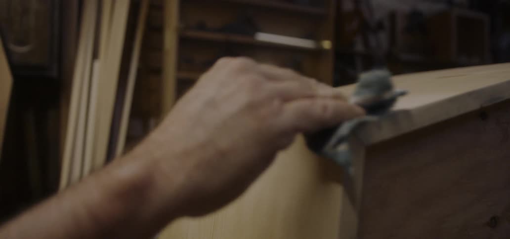 A carpenter wipes wood in a workshop