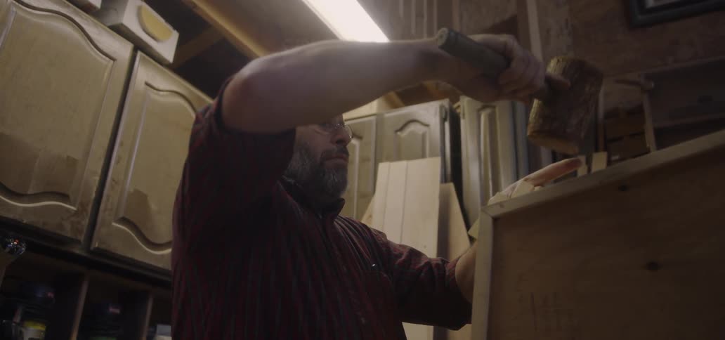 A man is repairing a cabinet inside at night