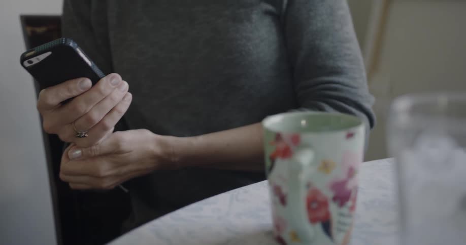 A woman is using her cell phone inside in daylight