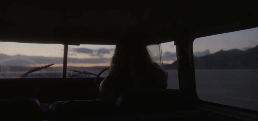 Person drives across a rural field at sunset