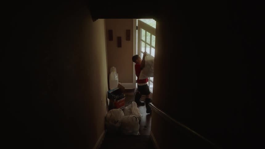 A young boy takes a trash bag outside