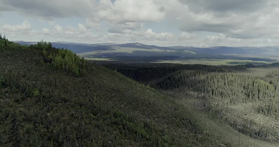 Clouds are casting shadows on a mountain landscape during the day
