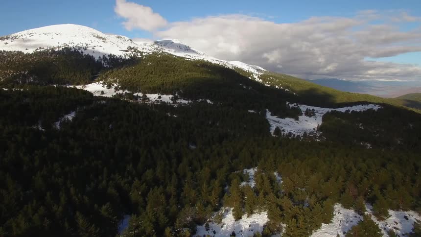 Clouds float above snowy mountains