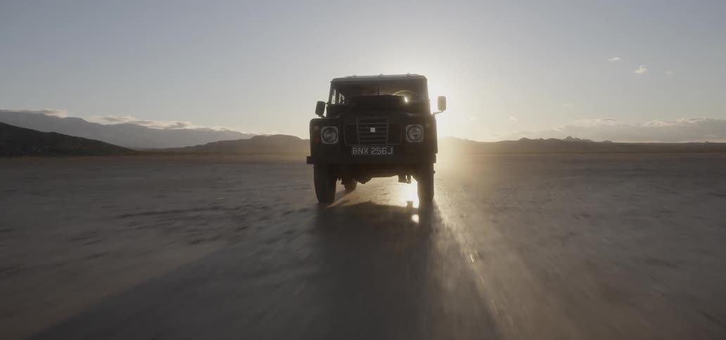 A truck races across the desert at sunrise