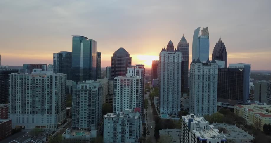 The sun sets behind skyscrapers