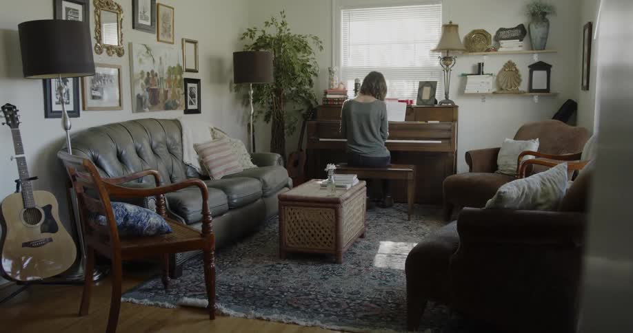 Woman practices a piano in a living room