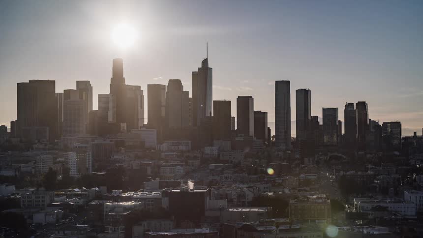 Vehicles travel along city streets as the sun rises