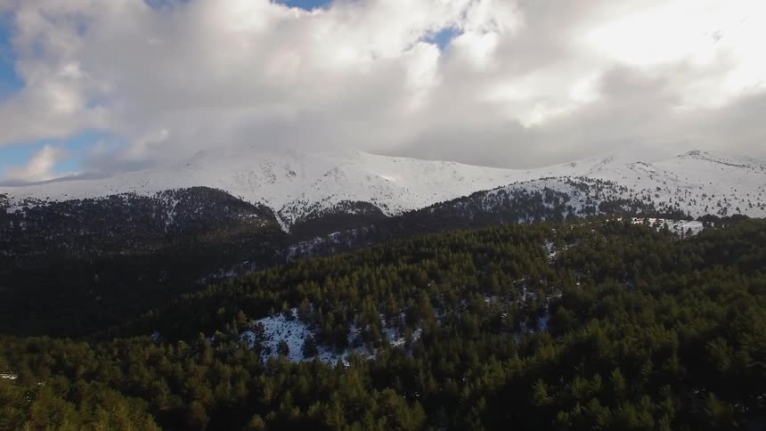 Clouds float over snowy mountains