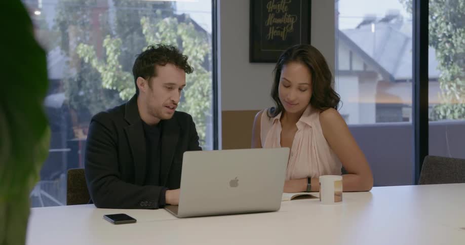 Two coworkers look at a laptop