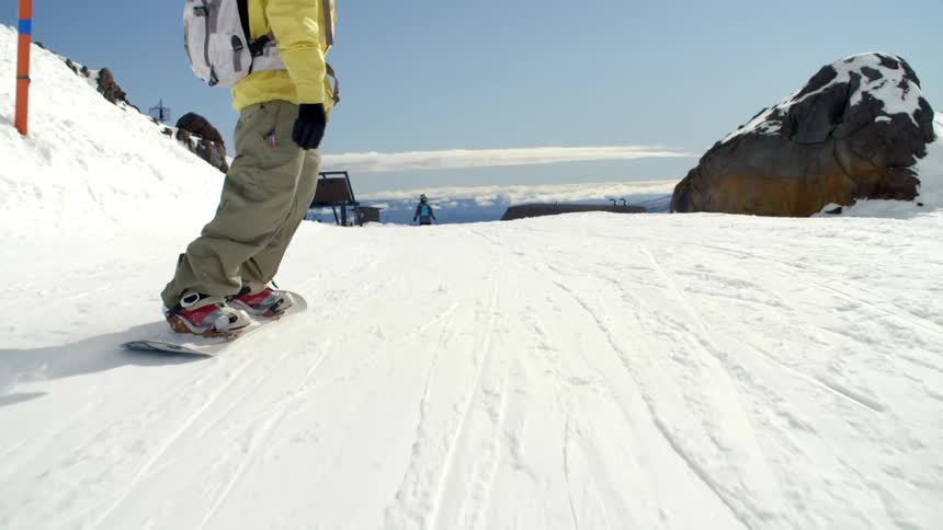 A man is snowboarding down a hill