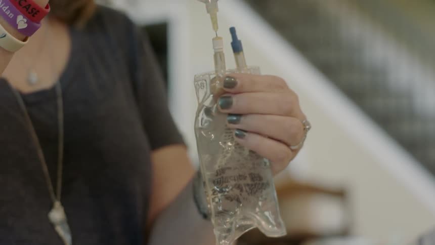A nurse inserts a needle into an iv bag