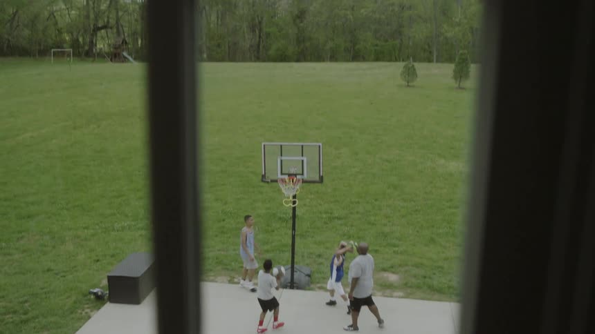 A group of kids and a man play basketball