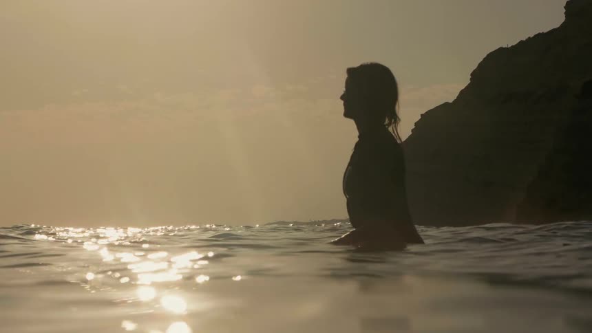 A woman resting on a surfboard in calm water