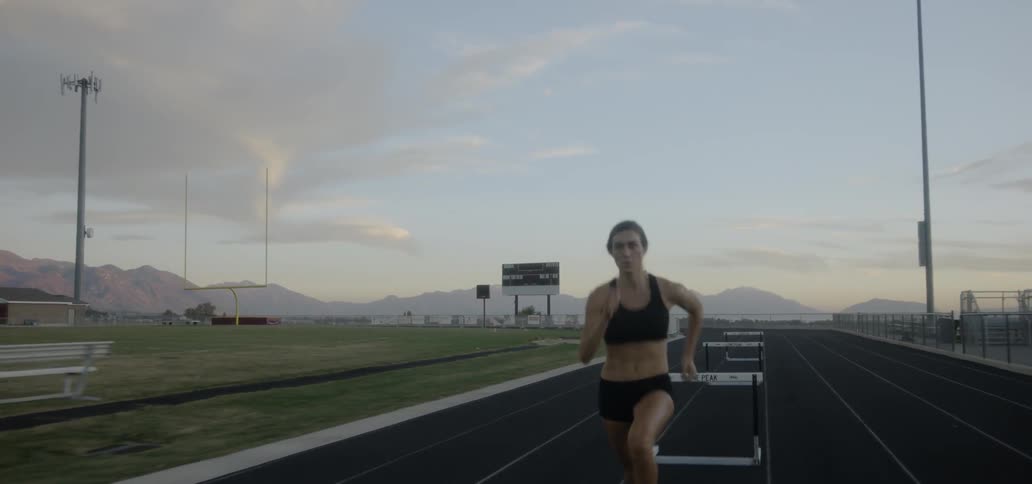 A woman jumps over hurdles on a track