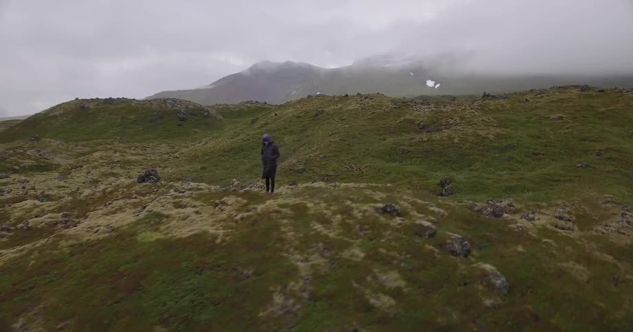 A hiker waves while standing on a hill