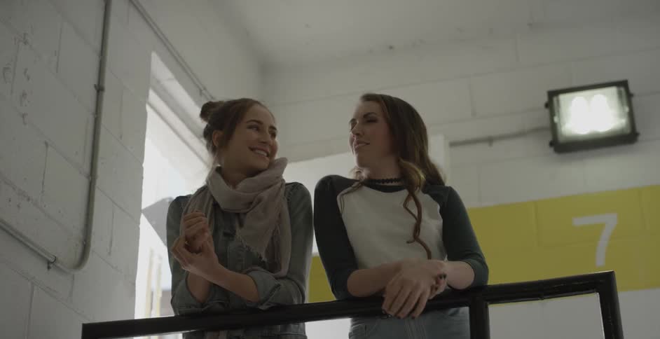 Two women lean over railing