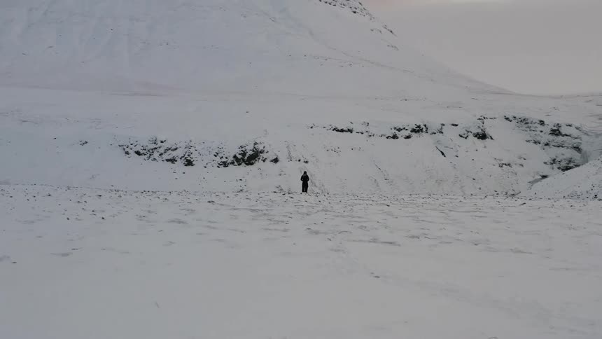 A person stands by the snow filled cliff