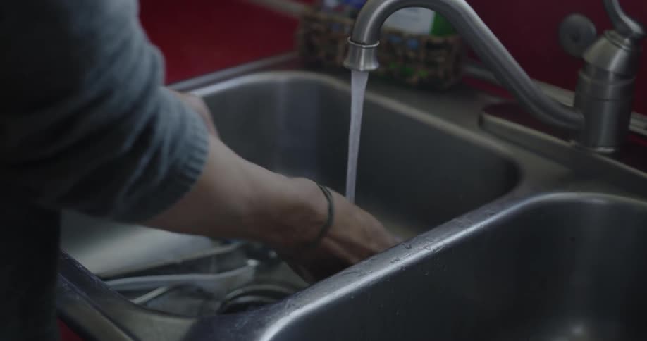 A person is washing dishes under the faucet
