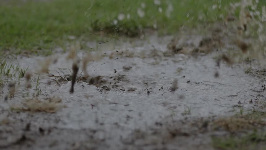 An athlete splashes in a puddle while it rains