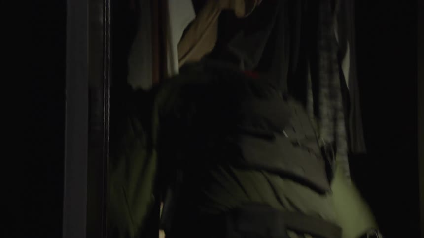 Man wearing a backpack searches through a closet
