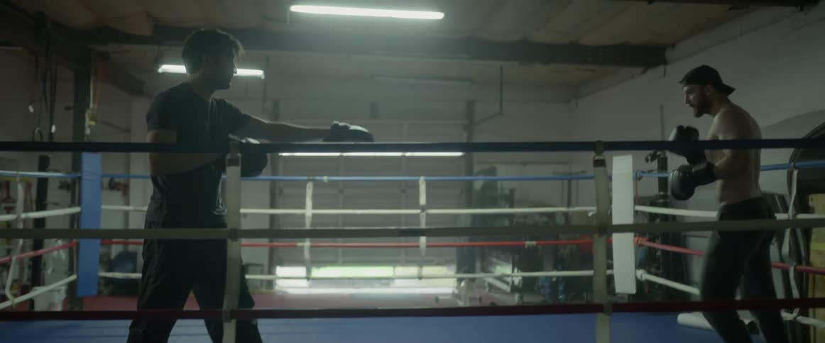Two men are circling each other as they are sparring in a boxing ring
