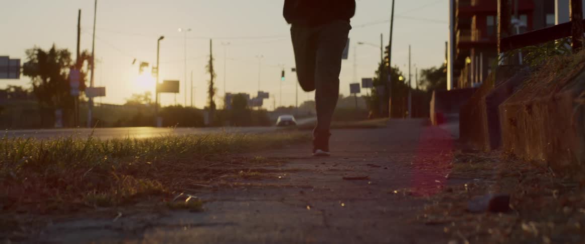 Man jogs on a sidewalk at sunrise