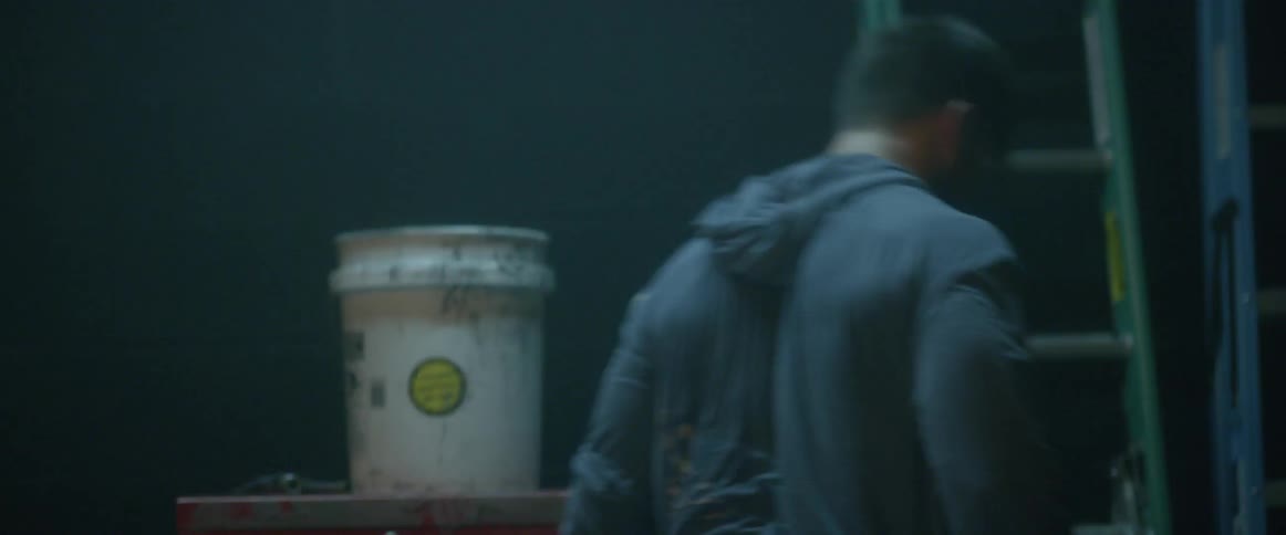 A man is tossing things about in a garage and clutching his head