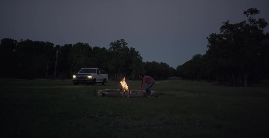 A truck drives up to a campfire
