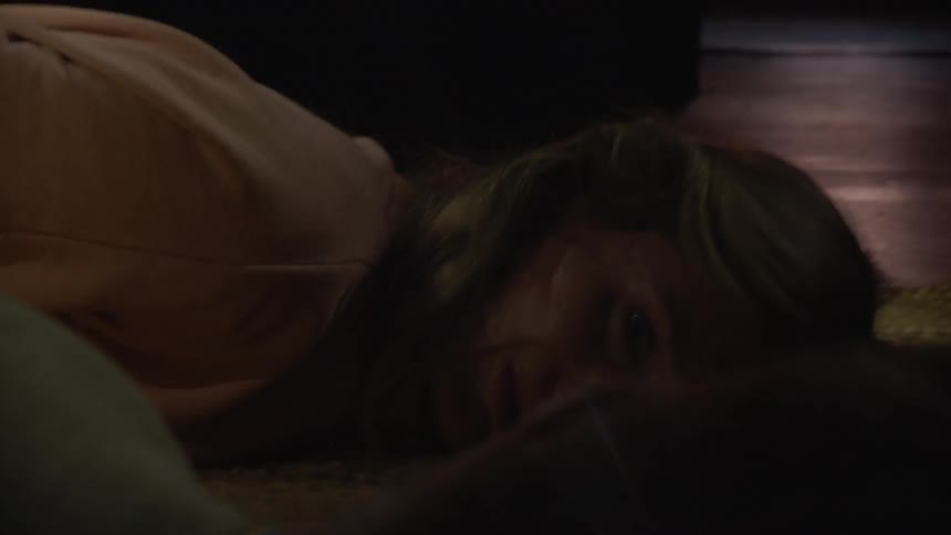 A woman is lying on the ground and crying as lights flash around her