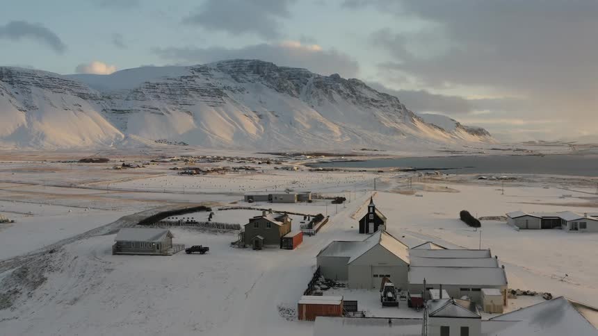 A group of buildings on snow covered land near mountains