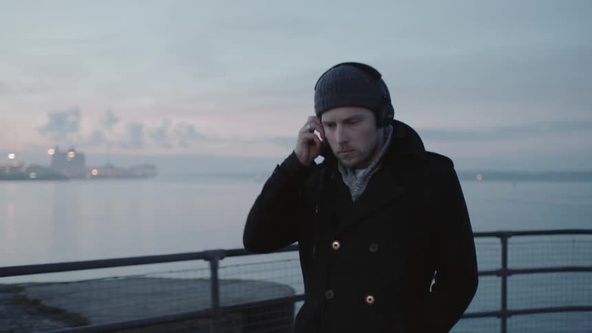 A man is walking outside listening to headphones