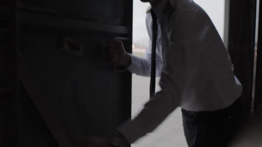 A pilot pushes open a hangar door at the airport