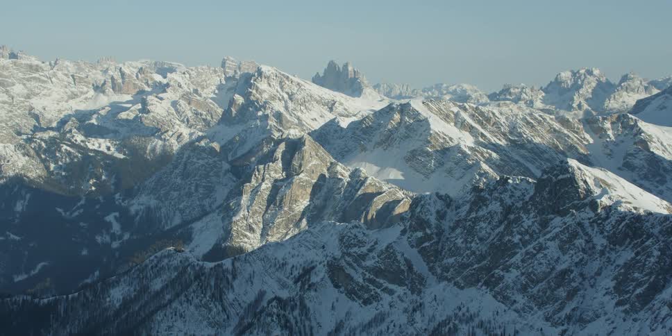 Snow is covering the slopes of a mountain range during the day