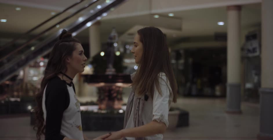 Woman grabs the hand of another woman walking through a mall and they both smile