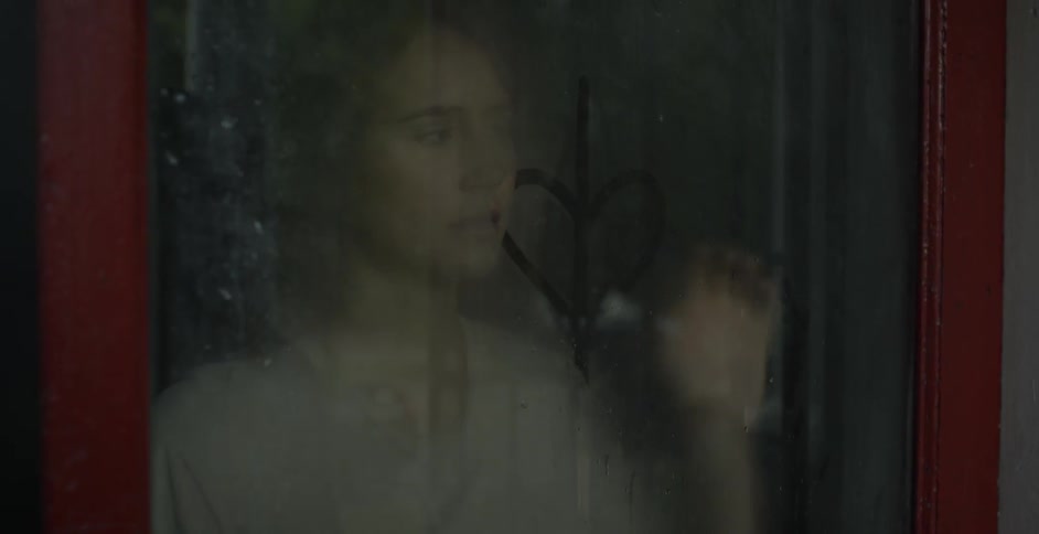 A woman presses her palm against the glass and a woman inside does the same
