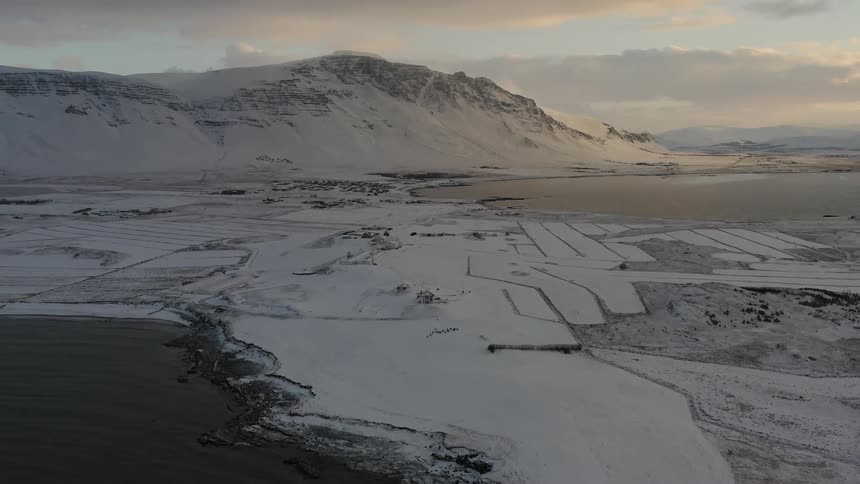 Snowy mountains and flat plains near a body of water