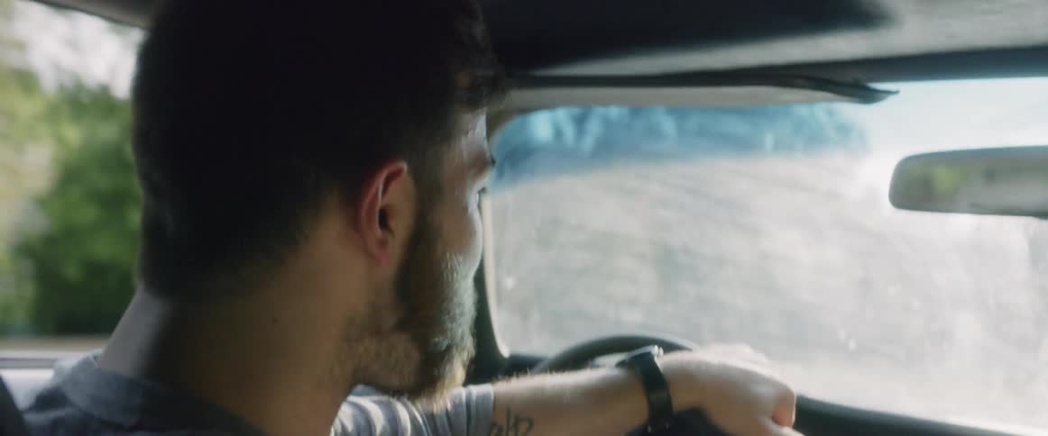 A man eats some food and takes a drink while driving