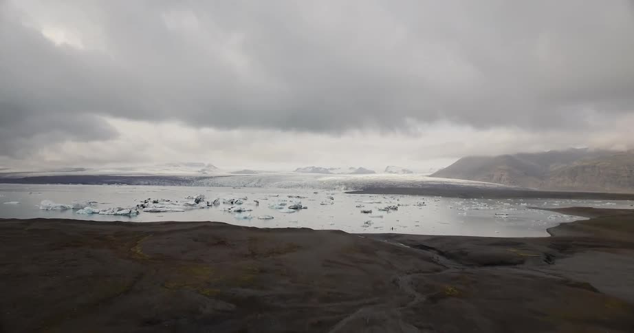 Grey clouds hang above the water and snow covered hills