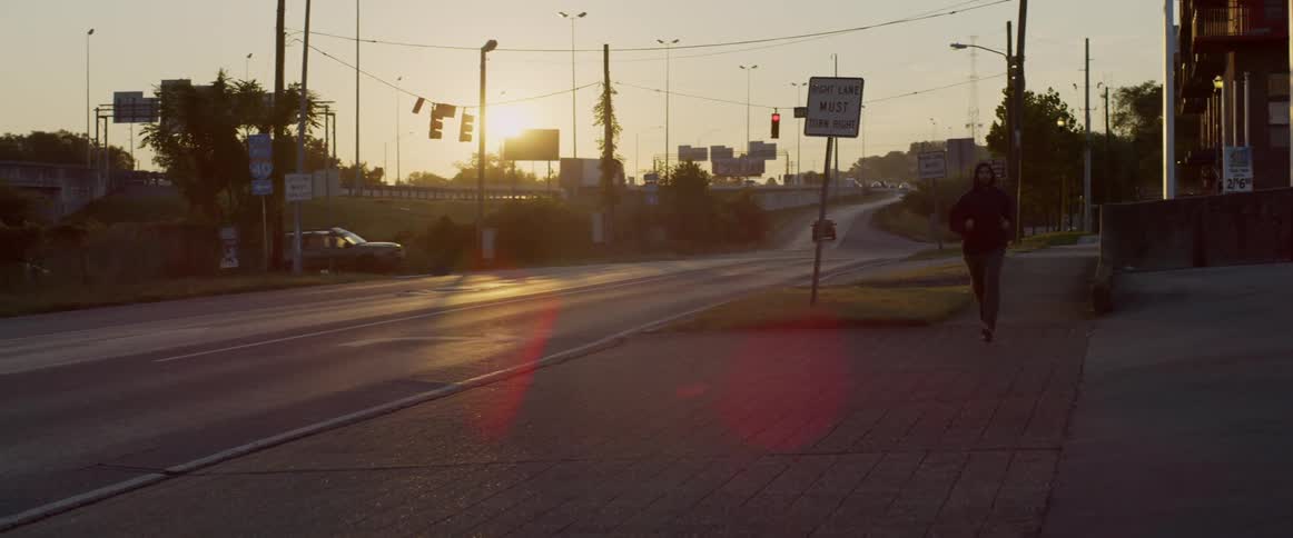 A man jogs on a sidewalk at sunrise