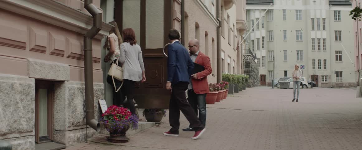 People walk through an open wooden door into an elegant city building.