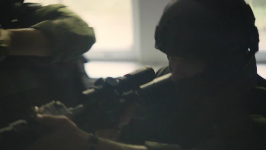 A tactical unit with weapons aimed makes its way up a stairwell