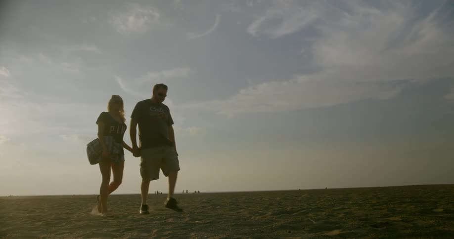 A couple walks across the beach