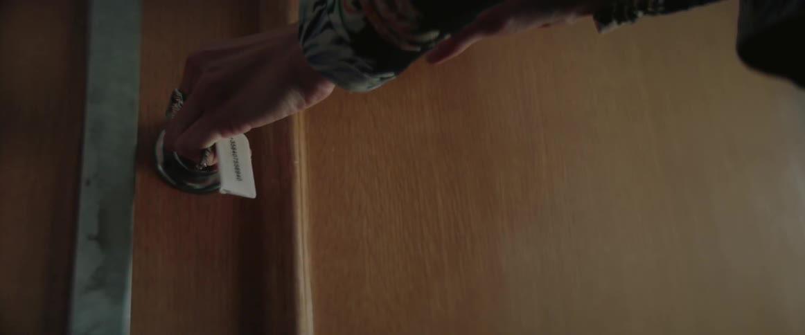 A person turns a key with a white tag to unlock a door.
