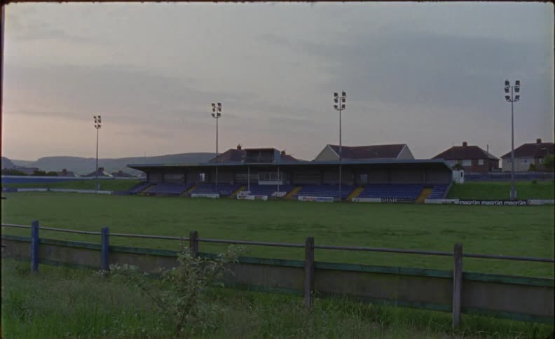 The sun sets over bleachers and a grass field