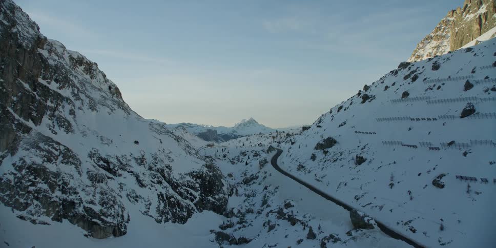A road goes around the snow covered mountain on a sunny day