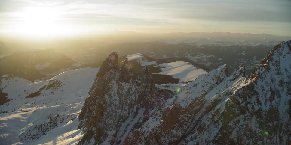 Sunlight is streaming onto a mountain range covered in snow