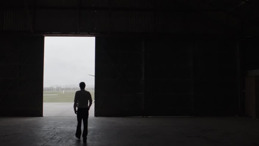 A man walks through the open hangar door to the airport