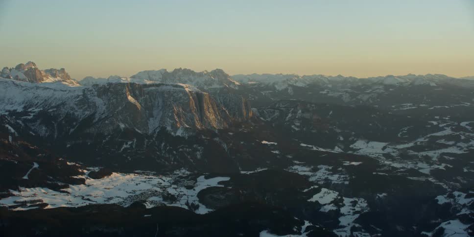 Sun sets behind snow covered mountains